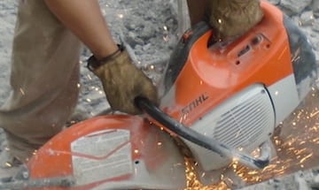 Person using a saw with protective gloves.