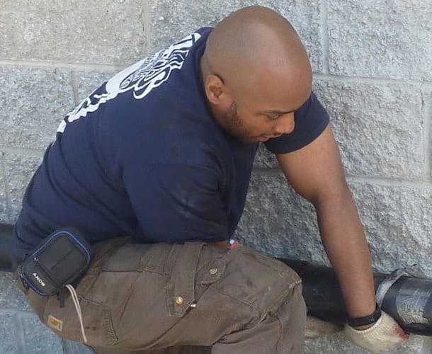 Person working on outdoor pipe installation.
