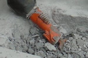 Jackhammer breaking concrete into small pieces.