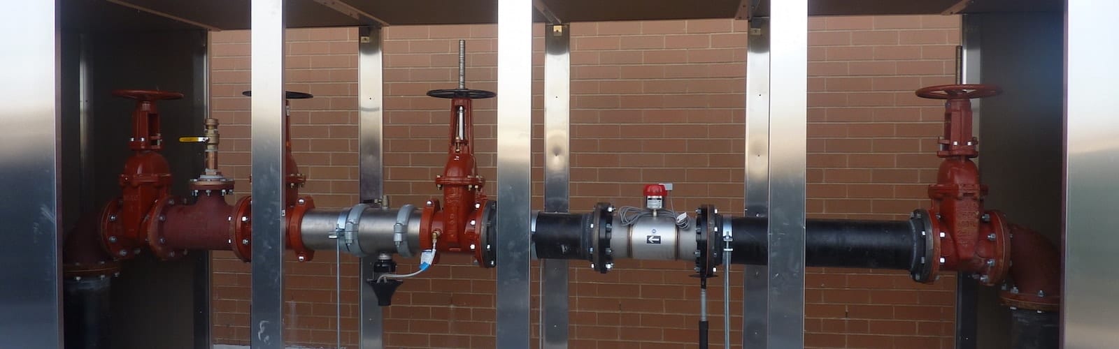Industrial valves and pipes against brick wall.