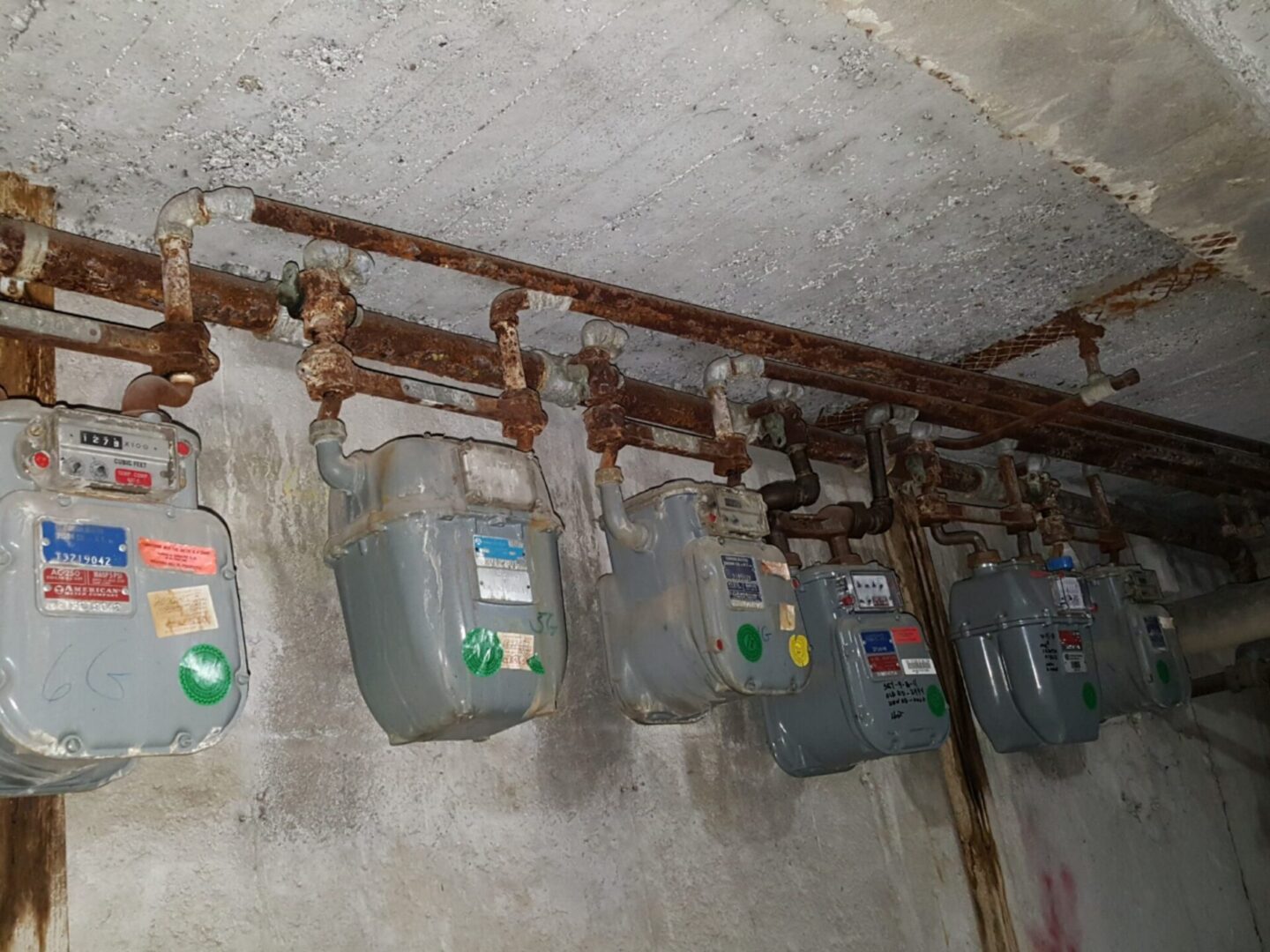 Rusty gas meters on a concrete wall.